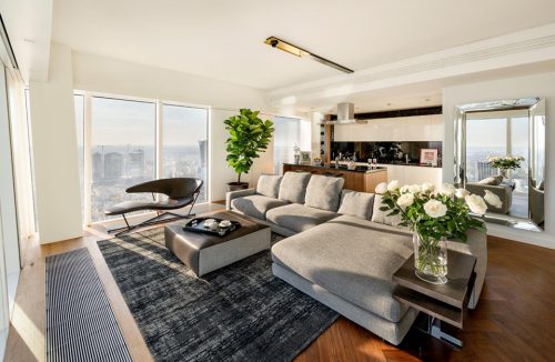 nowoczesny apartament projektu Anny Koszeli z dużą szarą sofą na tle biało czarnego aneksu kuchennego na Złotej 44