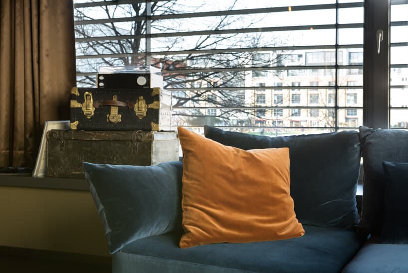 eleganckie wnętrze apartamentu w stylu Bohema od Wnętrza Michała niebieska sofa obok szafki ze starymi walizkami