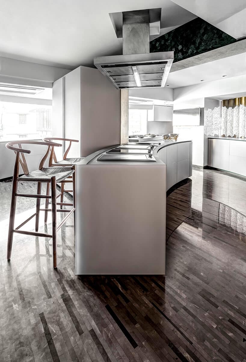 ekskluzywny apartament projektu ZZ Architects białe kuchnia z zaokrągloną biała wyspą na ciemnej podłodze z cienkich długich pasków kamieni