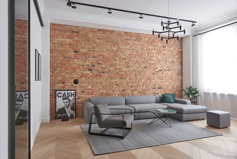 salon w apartamencie szarymi meblami do siedzenia na tle ceglanej ściany