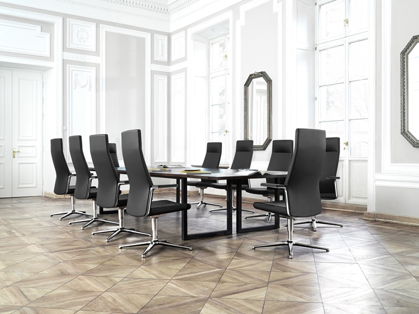 biała sala konferencyjna z drewnianą podłogą z czarnym stołem z eleganckimi czarnymi fotelami