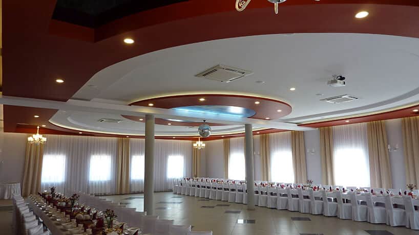 duża sala weselna ze stołami ustawionymi pod dwoma ścianamy