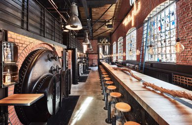 industrialne wnętrze restauracji Zoni z długim drewnianym barem na tle ceglanej ściany