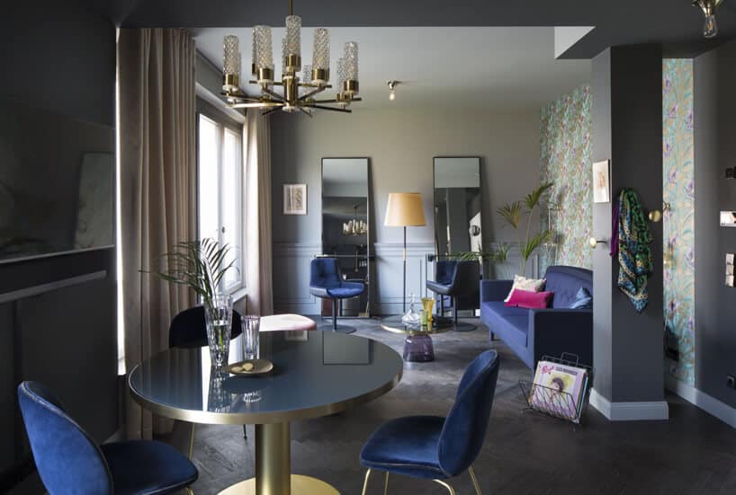 niebieskie krzesła niebieska sofa okrągły stolik prostokątne lustra szare filary w eleganckim pokoju