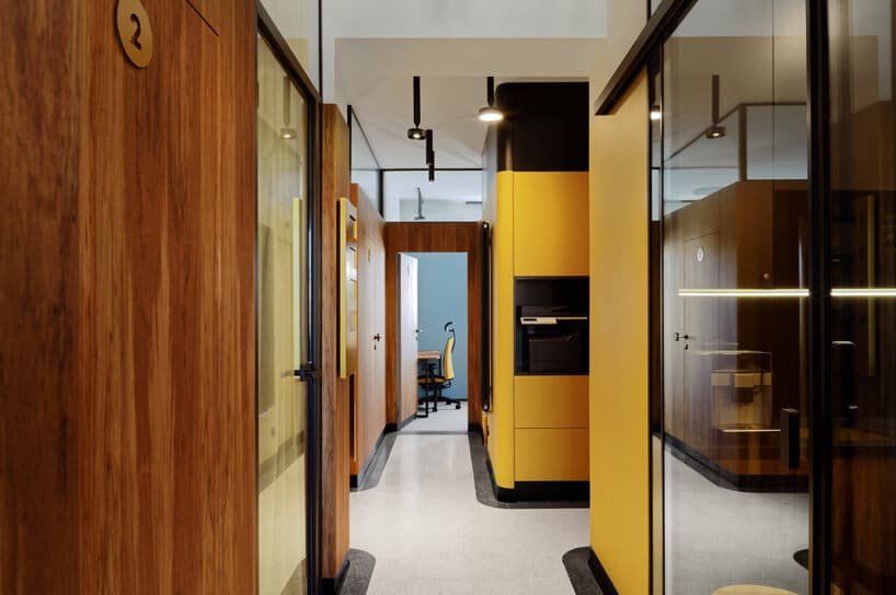 brązowe wnętrze Warszawski Ul od Beza Projekt korytarz wykończony drewnem żółtym plastikiem i szkłem