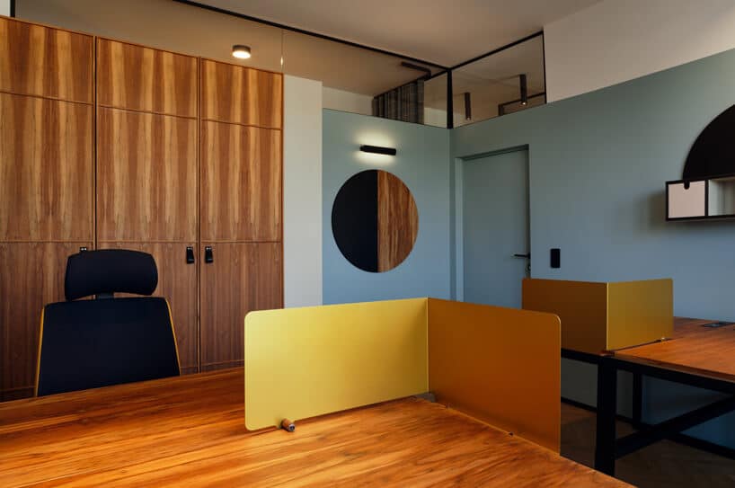 brązowe wnętrze Warszawski Ul od Beza Projekt biuro z niebieskimi ścianami w zestawieniu z drewnianymi szafami i biurkami