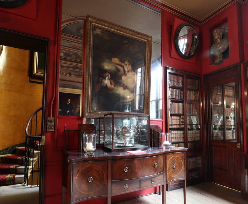 stare wnętrze Domu Architekta projektu Johna Soane’a z dużym lustrem na ścianie za obrazem oraz czerwonymi ścianami