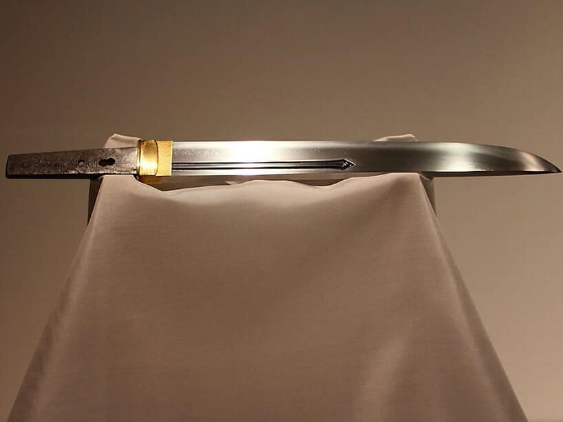 samo ostrze samurajskiego miecza ze złotym wykończeniem na atłasowej podporze