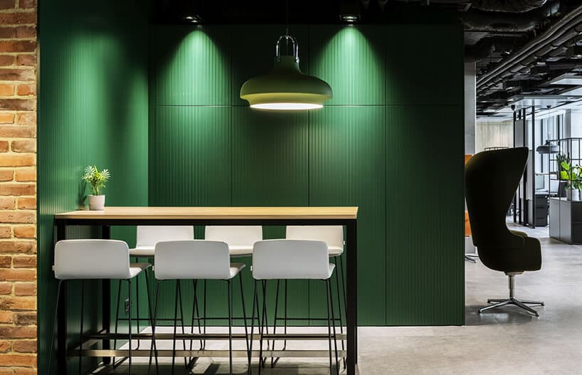 aranżacja biura Stalgast od MADAMA wysoki syolik z sześcioma białymi wysokimi stołkami na tle zielonej ściany