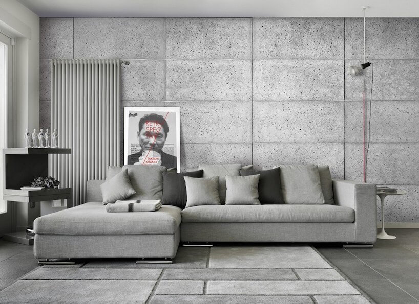 salon w jednolitych kolorach szarości z sofą dużym grzejnikiem na tle ściany z betonowych bloków
