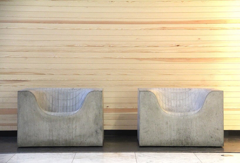 dwa betonowe fotele na tle drewnianej ściany