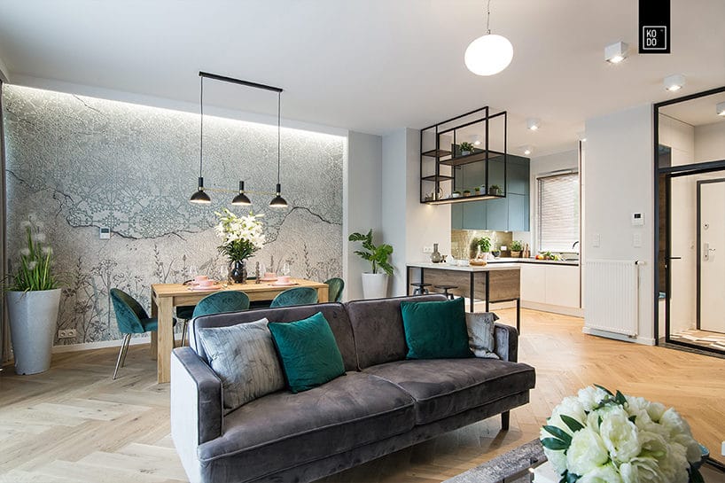 otwarty salon z drewnianą podłogą dużą sofą pośrodku na tle drewnianego stołu jadalnego