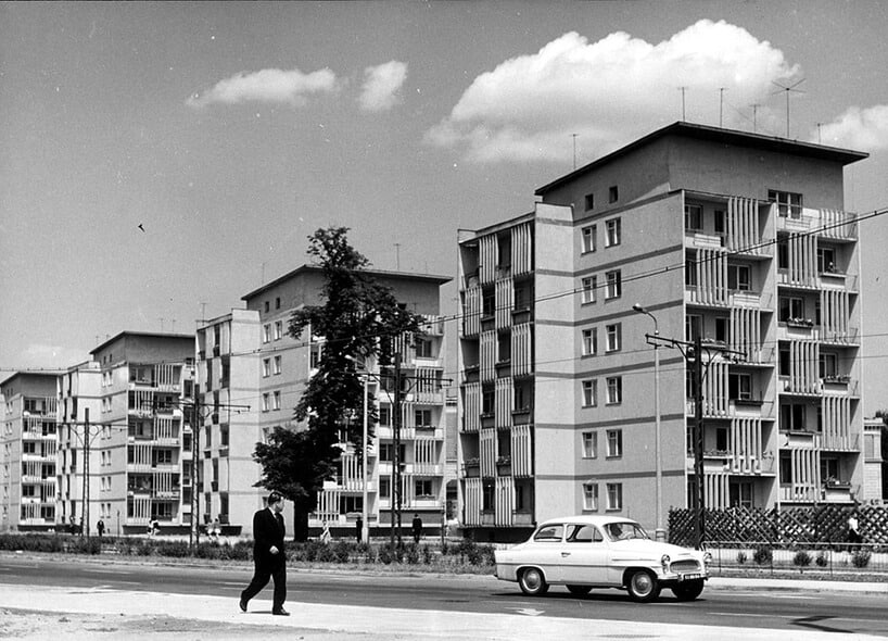 stare czarno-białe zdjęcie z białym starym samochodem na tle niedużych bloków mieszkalnych