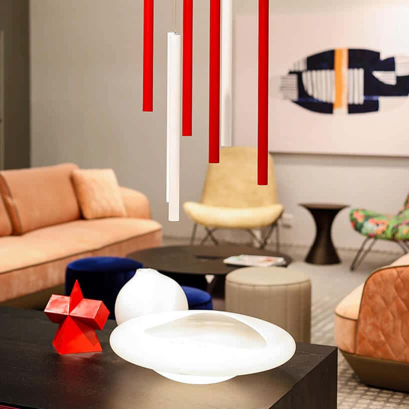 aranżacja stoiska na Furniture China 2018 z pastelowymi sofami czarnym stołem i podłużną biało czerwoną lampą