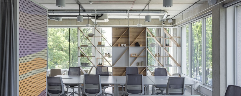 przestrzeń biurowa w Concordia Design szare biurka i krzesła na tle mebli z drewnianych