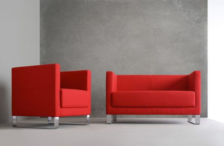 czerwona sofa i czerwony fotel na tle szarej ściany i podłogi
