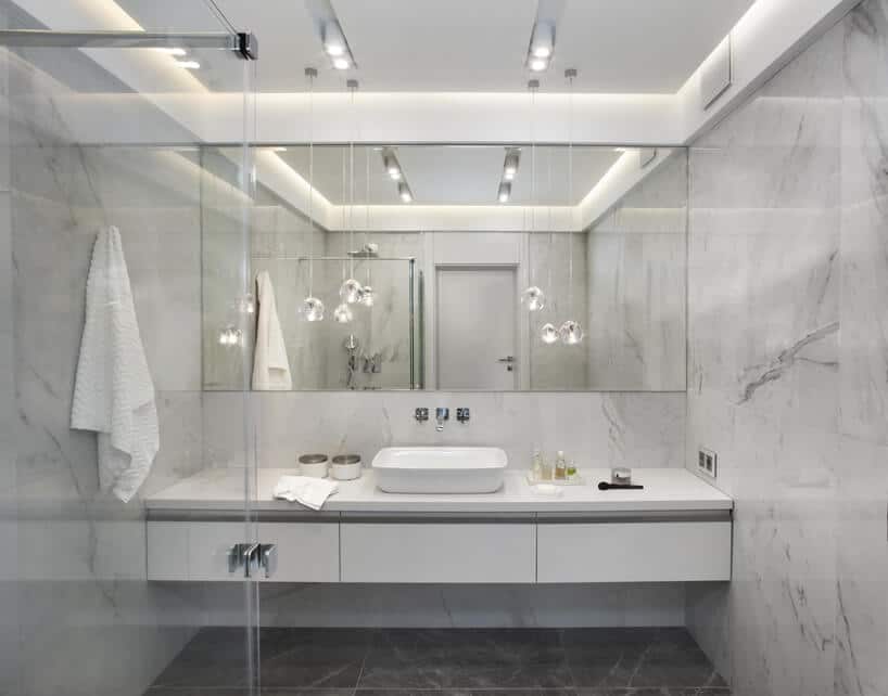 eleganckie wnętrze apartamentu projektu Rolanda Stańczyka biała łazienka z lustrem na całą ścianę za umywalką