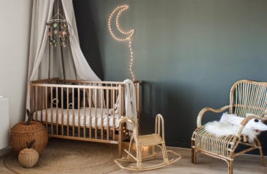 drewniane eleganckie łóżeczko od Woodies Safe Dreams w dużym pokoju z ciemnozieloną ścianą i świecącym księżycem