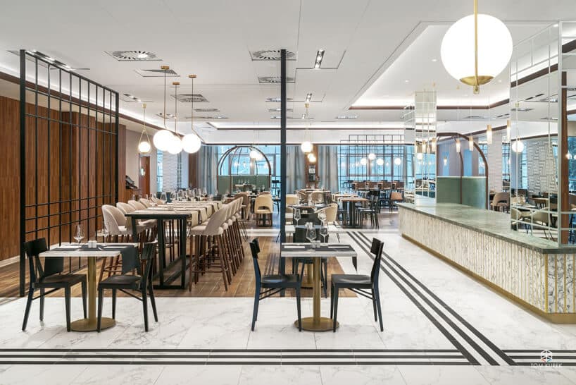 wnętrze części restauracyjnej Metropolo róznymi stolikami pod dużymi biało złotymi lampami