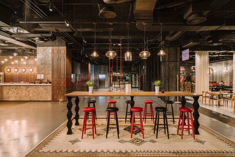 recepcja i poczekalnia w ibis Styles Sarajevo z dużym drewnianym stołem z czarnymi i czerwonymi stołkami