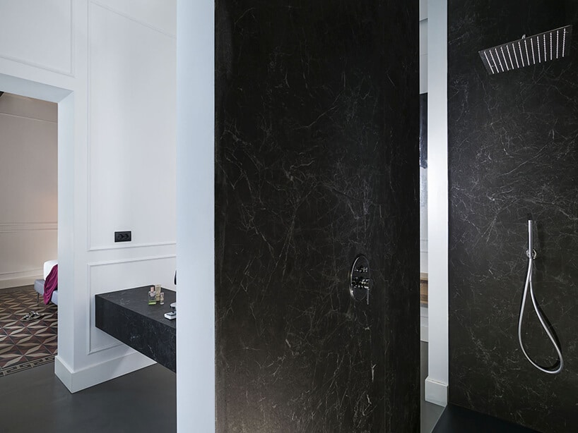 spieki kwarcowy Laminam w hotelu Habitat elegancki natrysk z czarną ścianą na tle białych ścian w pozostałej części łązienki