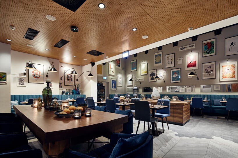 duże brązowe drewniane stoły z niebieskimi krzesłami w części restauracyjnej hotelu Indigo