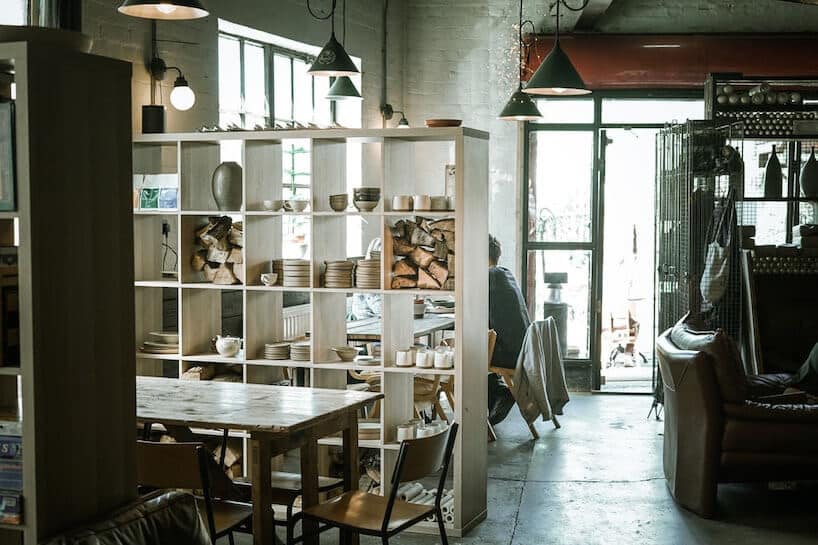 industrialne wnętrze restauracji ze starym stołem i szkolnymi krzesłami pod industrialnymi lampami