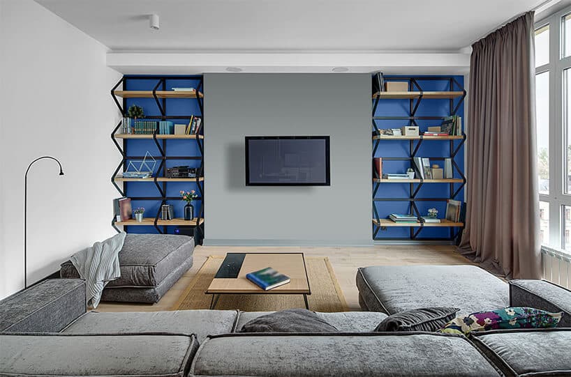 dwie niebieskie wnęki z półkami w szarej ścianie z telewizorem