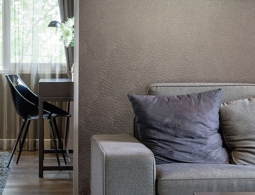szara sofa na tle ściany z tapetą
