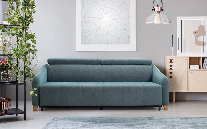 jasno niebieska kanapa w szarym pomieszczeniu z dywanem
