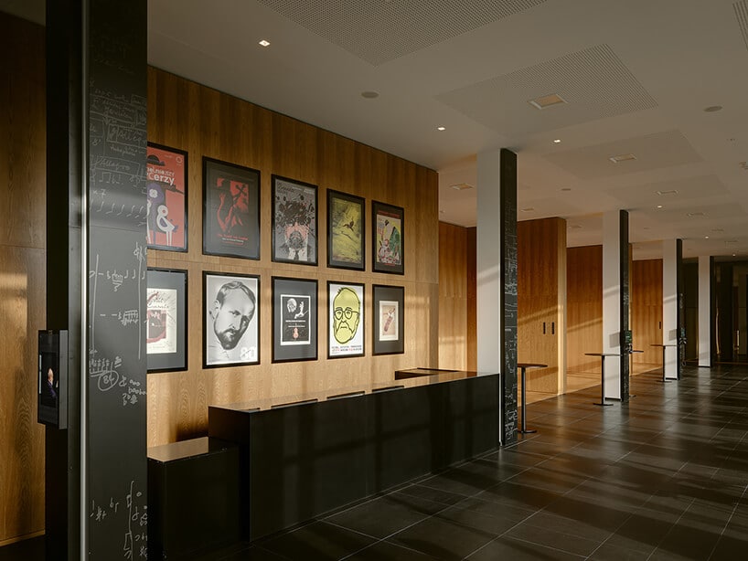 czarno biało brązowe wnętrze z kilkoma plakatami na ścianie z podobizną Krzysztofa Pendereckiego projektu Nizio Design International