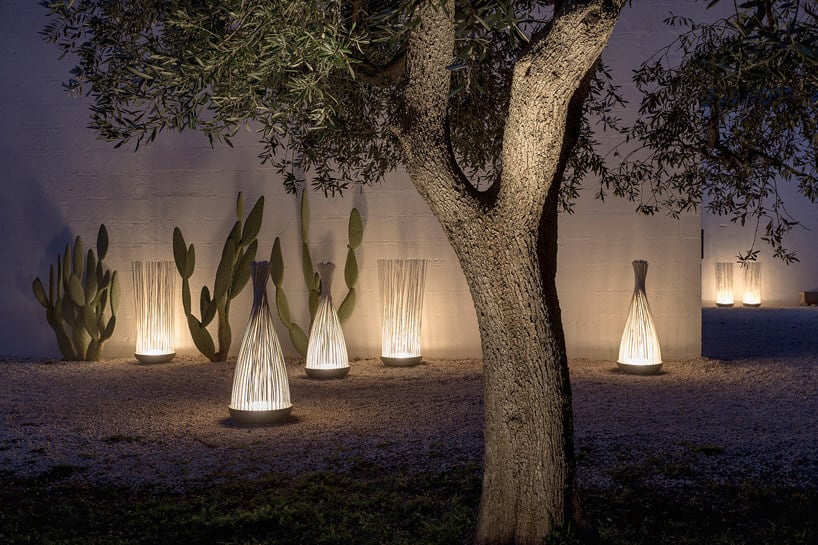 ogród oświetlony nietypowymi lampami z dużym drzewem