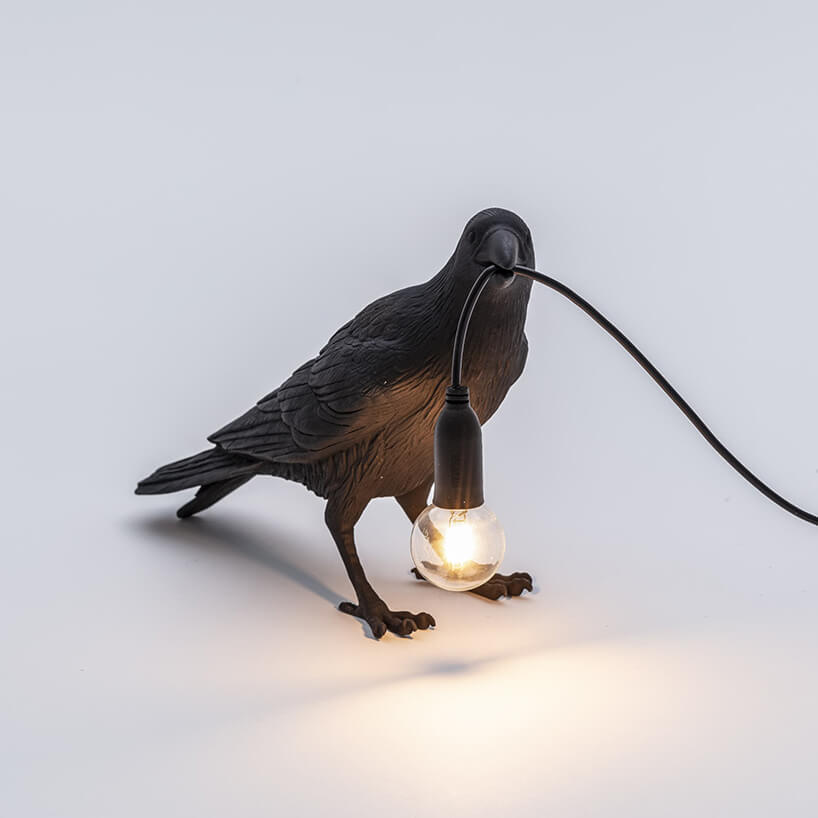wyjątkowa czarna lampka Bird Corbeau Waiting od Seletti w kształcie kruka trzymającego kabel z odsłoniętą żarówką