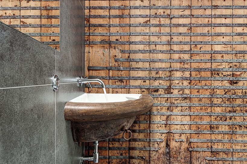 wyjątkowa łazienka z narożną umywalką na tle ściany ze starych desek ze starym metalowym wzmocnieniem od AR Design Studio