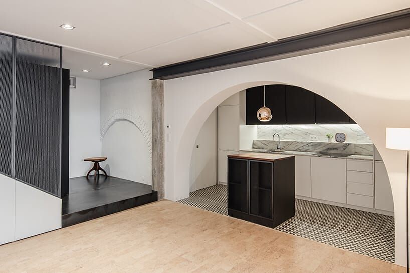 loft projektu KEMA studio biało czarna kuchnia z małą wyspą pod łukiem wejściowym