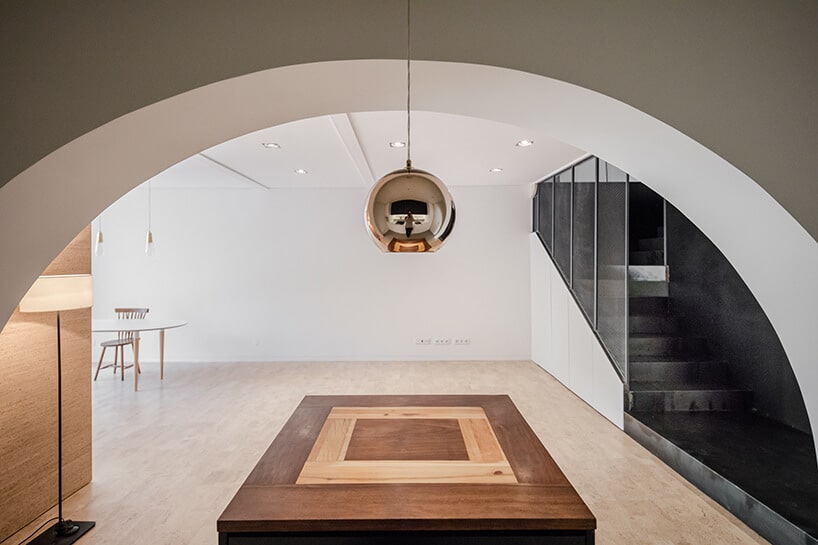 loft projektu KEMA studio drewniany niski stół pod białym łukiem wejściowym