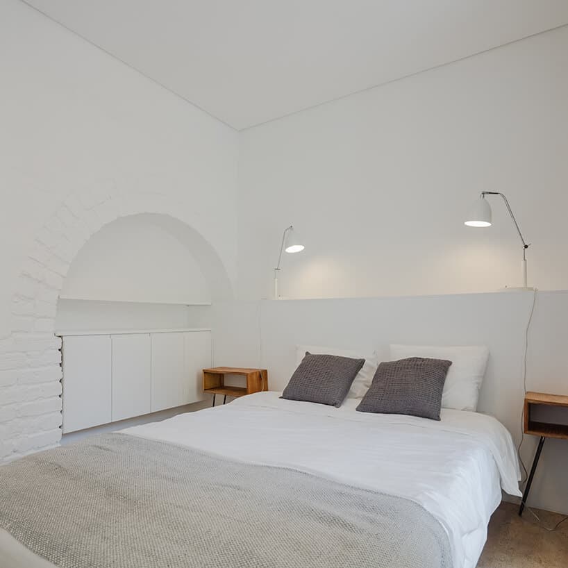 loft projektu KEMA studio biała sypialnia z dużym łóżkiem pomiędzy dwoma małymi szafkami nocnymi