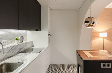 loft projektu KEMA studio biała kuchnia z kamiennym białym blatem pod czarnymi szafkami górnymi i podłoga i biało czarne trójkąty