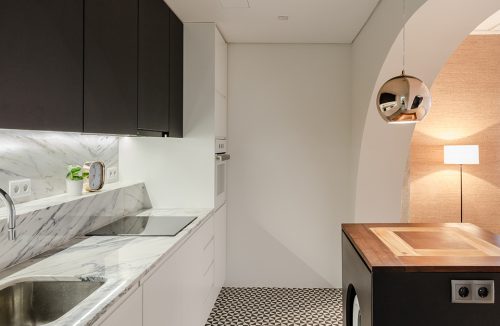 loft projektu KEMA studio biała kuchnia z kamiennym białym blatem pod czarnymi szafkami górnymi i podłoga i biało czarne trójkąty