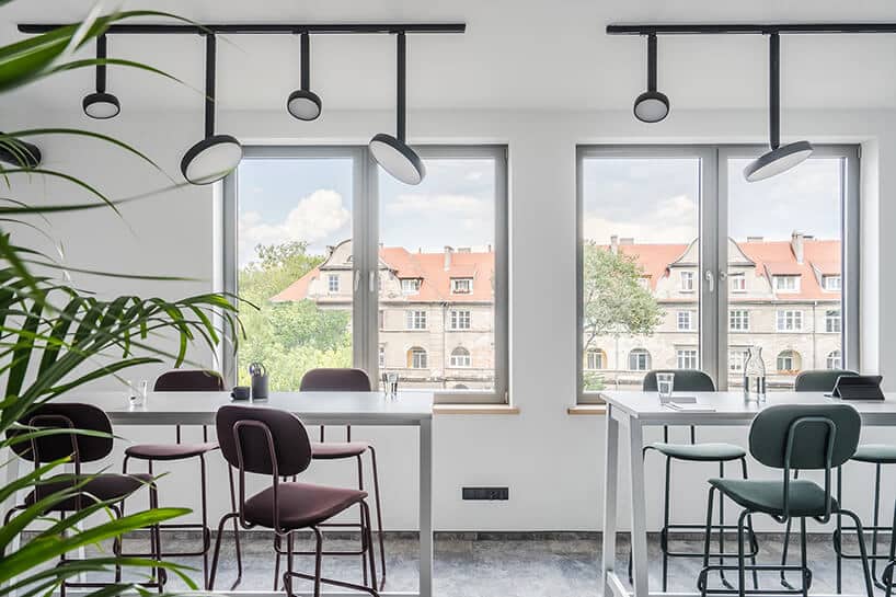 nowoczesna przestrzeń biurowa MDD Work Together białe wyższe biurka z krzesłami na tle okien z widokiem na kamienice