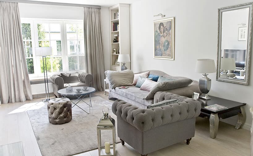 eleganckie wnętrze projektu MIśkiewicz Design salon szara sofa z dwoma szarymi fotelami i błyszcząca pufą