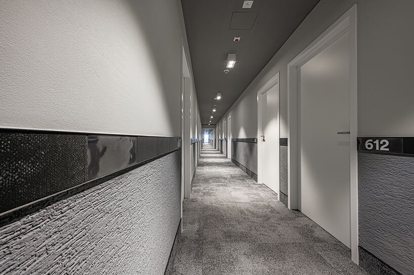 szary nowoczesny korytarz hotelowy z białymi drzwiami