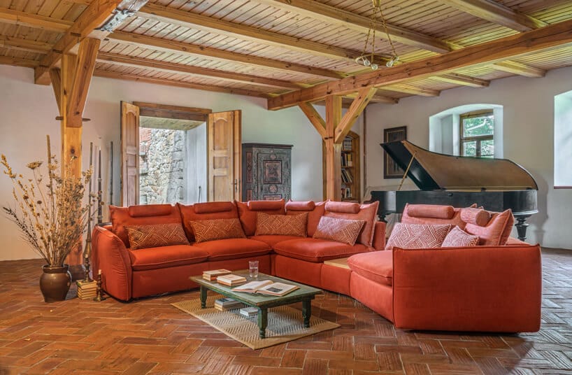 pomarańczowy system modułowy Merida od Gala Collezione w eleganckim salonie z drewnianm sufitem i drewnianymi słupami