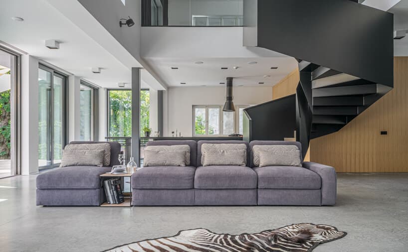 szara modułowa sofa Serena od Gala Collezione w przestronnym salonie na tle schodów i białego piętra