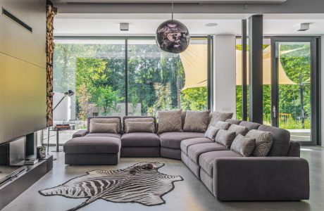 szara modułowa sofa Merida od Gala Collezione w przestronnym salonie obok skóry z białego tygrysa