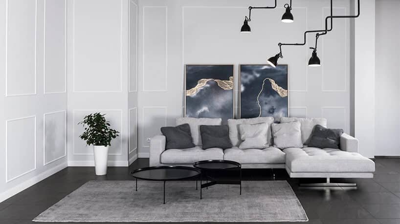 szara sofa narożna w salonie z czarną podłogą i szarymi ścianami