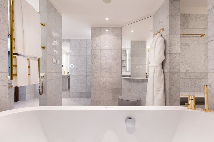 hotel Sofitel aranżacja apartamentu przestronnej łazienki w szarych kamiennych płytkach i dodatkach w złotym kolorze