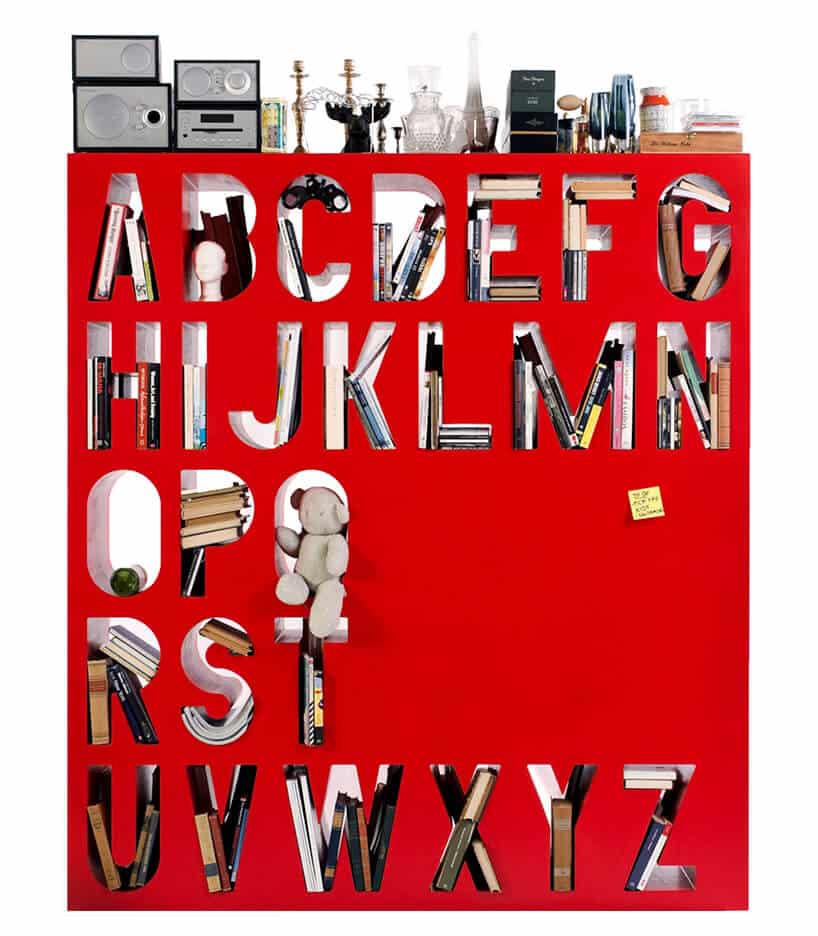 nowoczesny regał na książki czerwony z wydrążonymi literami alfabetu jako półkami z bliska