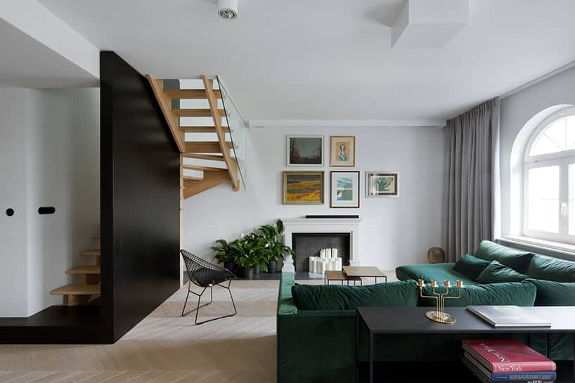 nowoczesny salon z drewnianymi schodami z kominkiem i zieloną narożną sofą