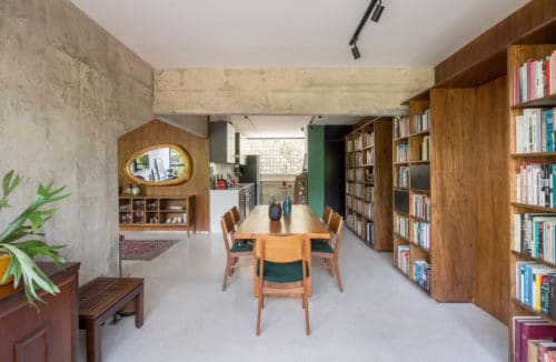 betonowo-drewniane duże wnętrze z regałami na książki oraz stołem i krzesłami w kolorze jasnego brązu